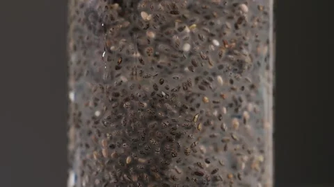 Chia seeds blending and rotating in water close-up macro black background. Dry Stock Footage 257086487
