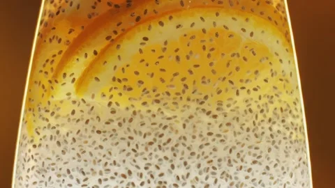 Chia seeds blending and rotating in water with lemon, orange close-up macro Stock Footage 259075250