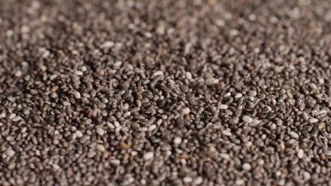 Chia seeds falling down on a plate close-up macro. Dry healthy ingredient Stock Footage 256678512