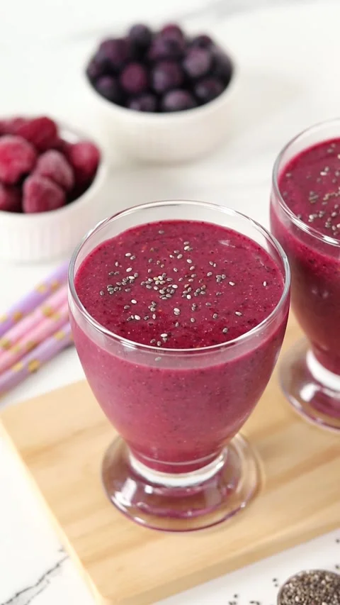 Chia seeds falling on top of raspberry blueberry smoothie Stock Footage 307618257