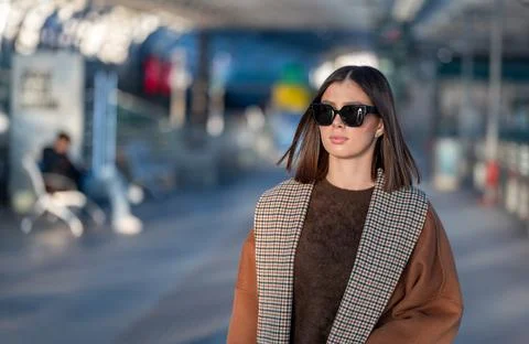 Chic brunette in sunglasses and a patterned lapel coat walks confidently do.. 库存照片
