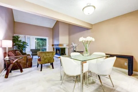 Chic dining area features modern glass table with white leather chairs. Conne Stock Photos