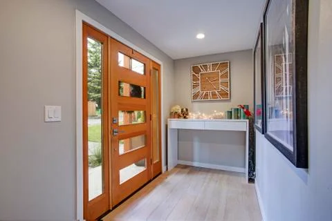 Chic foyer features a glass panel front door flanked by skylights, white cons Stock Photos