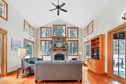 Chic living space with tons of light, high vaulted ceiling and stone fireplac Stock Photos