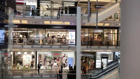 Chic multi-level shopping mall interior featuring glass storefronts, escalators, Stock Footage 305175886