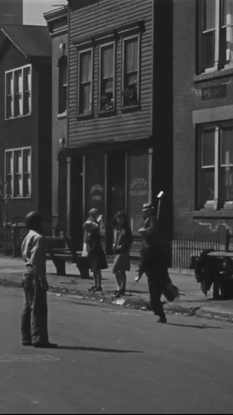 CHICAGO - 1930s - Traffic periodically interrupts a pickup game of baseball Stock Footage 338391968