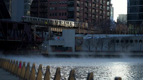 Chicago River in winter with elevated train moving past downtown buildings, cold Stock Footage 328071493