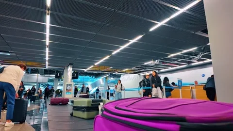 Chicago, USA, 7 May 2026: Colorful suitcases on baggage carousel with travelers Stock Footage 336339035