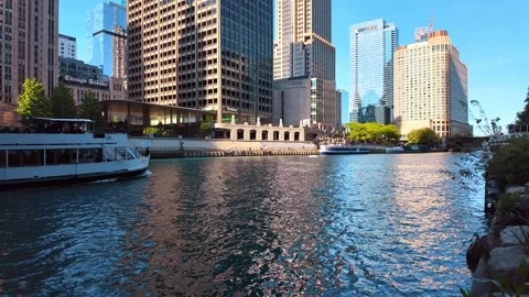 Chicago, USA, 7 May 2026: Sunlit skyscrapers along Chicago River with tour boat, Stock Footage 336339079