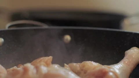 Chichen legs being fried in a frying pan. Steam is coming from the chicken legs Stock Footage 256614276