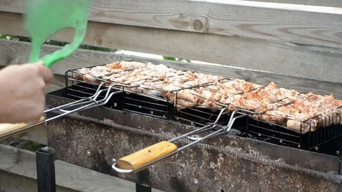 Chicken appetizing meat is fried on the grill, a man fanning the fire for heat Stock Footage 112434077