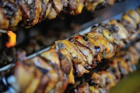 Chicken baking on skewer in barbecue in kitchen Stock Photos