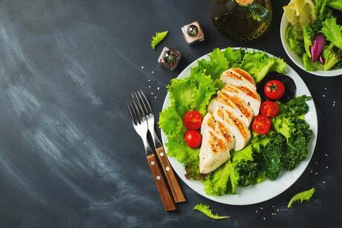 Chicken breast fillet and vegetable salad with tomatoes and green leaves on a Stock Photos