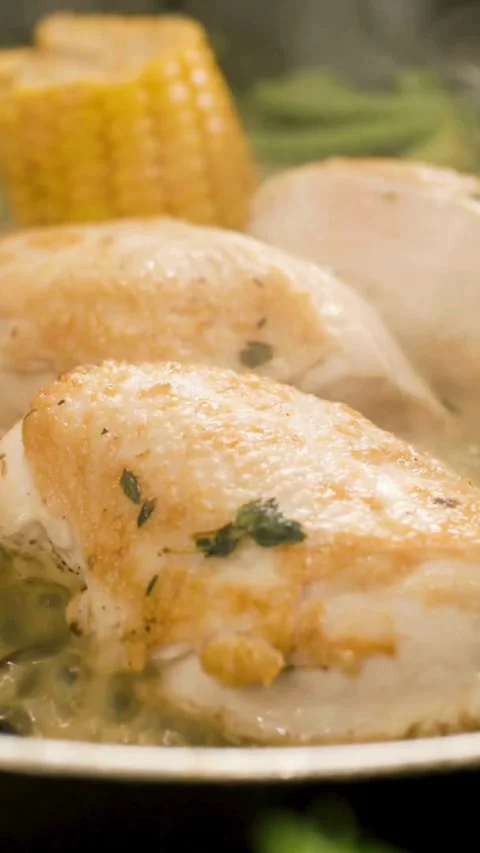 Chicken breast fillets sizzle in pan with fresh corn Stock Footage 334169796