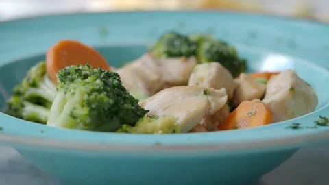 Chicken with broccoli and carrots served in a blue bowl Stock Footage 348473653