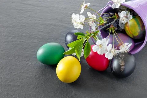 Chicken bucket  with painted Easter eggs on dark tabletop. Concept creative.. Stock Photos