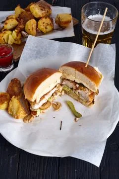 Chicken burger cuted in two halfs with potatoes and beer Stock Photos