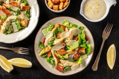 Chicken Caesar salad, overhead flat lay shot with lemons and dressing Stock Photos