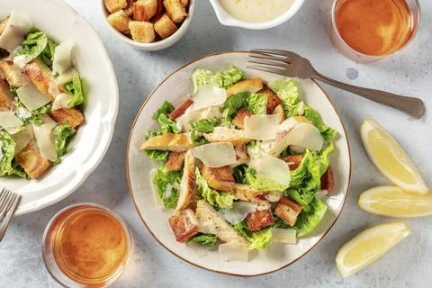 Chicken Caesar salad, overhead flat lay shot with wine and lemons Stock Photos