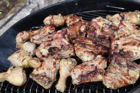 Chicken drumsticks are cooked over a fire on a barbecue grill. Stock Photos