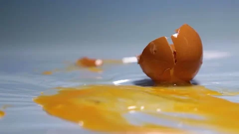 A chicken egg breaks from falling onto a table. Stock Footage 157327543