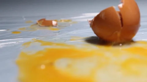 A chicken egg breaks from falling onto a table. Stock Footage 157327597