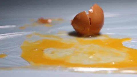 A chicken egg breaks from falling onto a table. Stock Footage 157327653