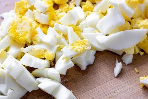 Chicken egg cut into small cubes on a brown board Stock Photos