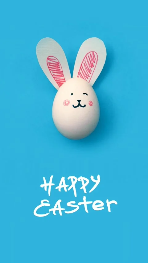 Chicken egg with cute bunny face and ears and text Happy Easter on blue Stock Footage 298408614