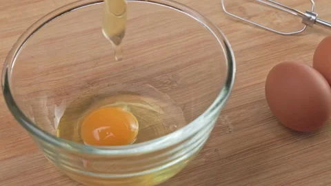 Chicken egg falls in slow motion into a glass bowl close-up. Stock Footage 220176445