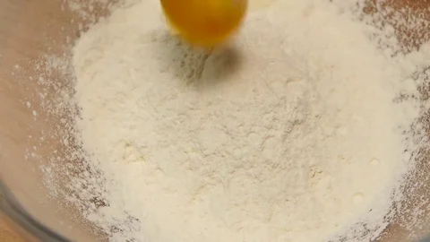 Chicken egg falls into wheat flour in slow motion, closeup Stock Footage 76167331