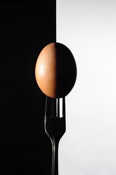 A chicken egg pierced by a fork with light forms like an eclipse Stock Photos