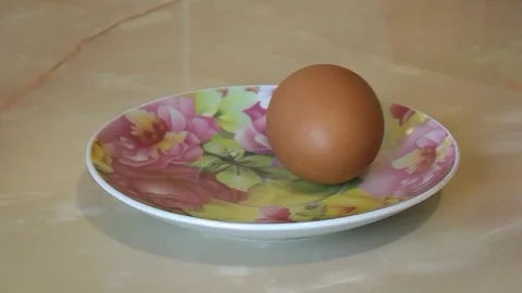 Chicken egg spinning on a plate Stock Footage 104360909