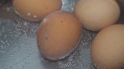 Chicken eggs are boiled in a pan in water on a gas stove close-up Stock Footage 128495212