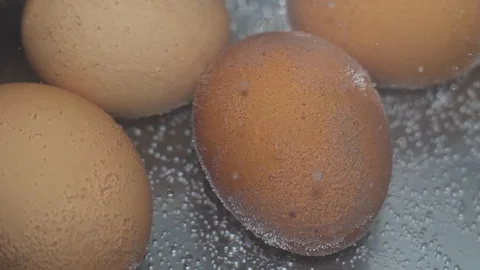 Chicken eggs are boiled in a pan in water on a gas stove close up Stock Footage 128495452
