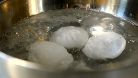 Chicken eggs boiling in bubbling water, nurturing process of cooking. Steaming Stock Footage 312846386