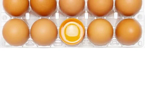 Chicken eggs in a clear plastic box with egg yolk in half of eggshell on whit Stock Photos