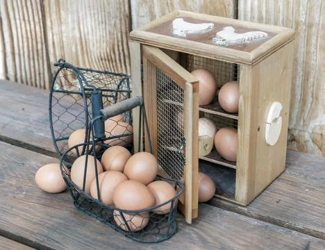 Chicken eggs in a decorative box anf metal baskets on a table in front of a.. Stock Photos