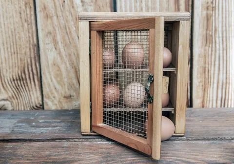 Chicken eggs  in a decorative box on a table in front of a wooden wall  bac.. Stock Photos