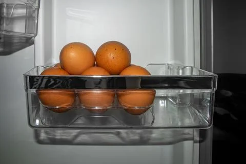 Chicken eggs in an egg cup on a shelf in the refrigerator Stock Photos
