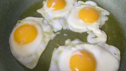 Chicken eggs in a frying pan while frying on stove. Video stock 269678479