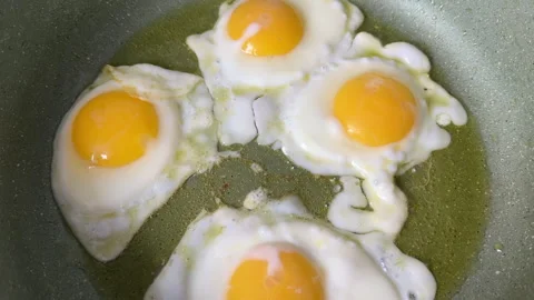 Chicken eggs in a frying pan while frying on stove. Video stock 269678692