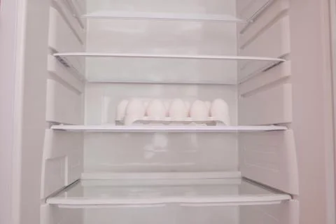 Chicken eggs standing on the empty shelf of the refrigerator in the egg tray Stock Photos