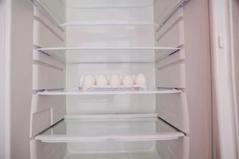Chicken eggs standing on the empty shelf of the refrigerator in the egg tray Stock Photos