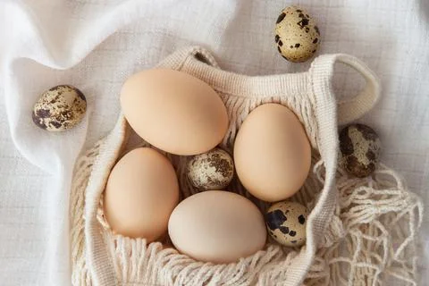 Chicken eggs in a string bag on white background, selective focus. Happy easter Stock Photos