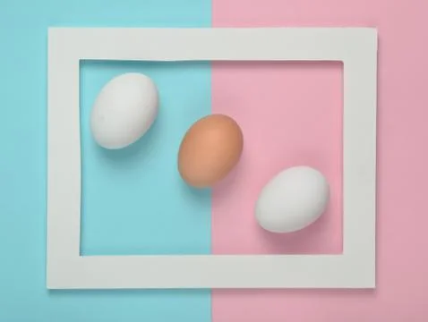 Chicken eggs in a white frame on a colored pastel background. Minimalist tren 库存照片