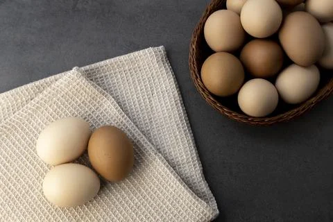 Chicken eggs in a wicker basket on the table. Eggs on a kitchen towel Stock Photos