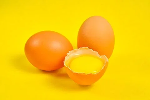 Chicken eggs on a yellow background broken with yolk. Stock Photos