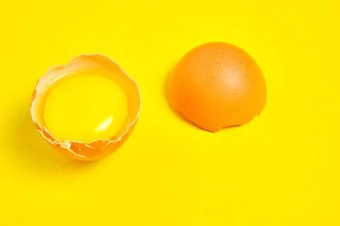 Chicken eggs on a yellow background broken with yolk. Stock Photos