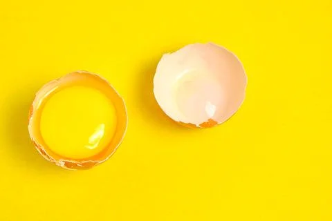 Chicken eggs on a yellow background broken with yolk. Stock Photos